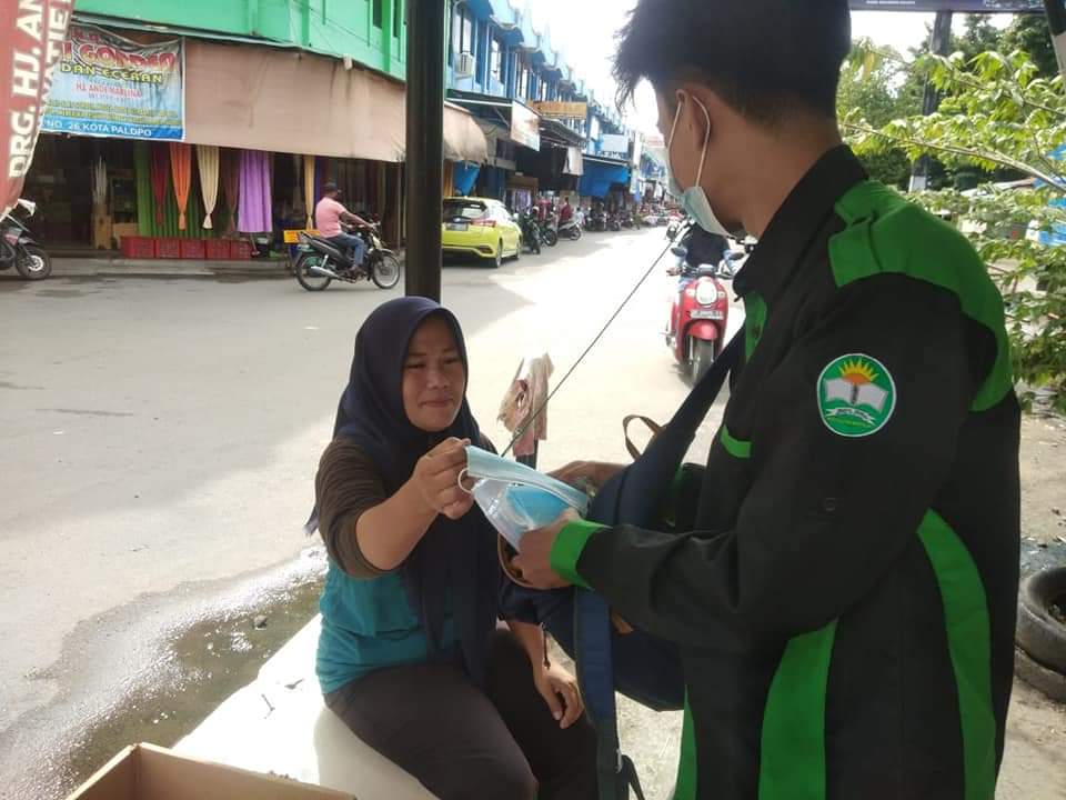 Terlihat salah satu pengurus HMPS PPKn membagikan masker kepada masyarakat, di pusat niaga Palopo, Minggu (27/7/21).