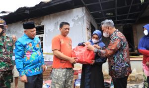 Bupati Budiman didampingi Ketua PKK Luwu Timur, Hj. Sufriaty beserta wakil ketua II DPRD, H. Usman Sadik dalam menyerahkan bantuan kepada keluarga korban kebakaran di Desa Asuli, Minggu (13/3/22).