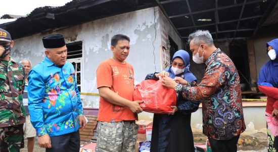 Bupati Budiman didampingi Ketua PKK Luwu Timur, Hj. Sufriaty beserta wakil ketua II DPRD, H. Usman Sadik dalam menyerahkan bantuan kepada keluarga korban kebakaran di Desa Asuli, Minggu (13/3/22).