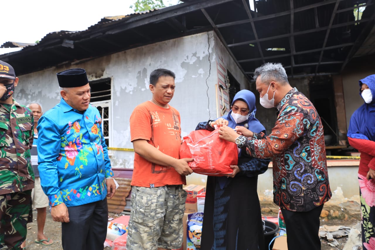 Bupati Budiman didampingi Ketua PKK Luwu Timur, Hj. Sufriaty beserta wakil ketua II DPRD, H. Usman Sadik dalam menyerahkan bantuan kepada keluarga korban kebakaran di Desa Asuli, Minggu (13/3/22).